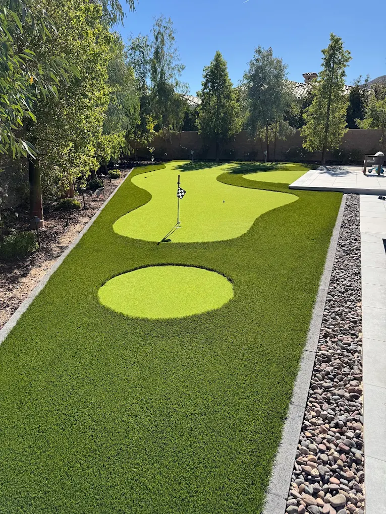 Synthetic putting green with consistent ball roll surrounded by decorative rock in a Henderson landscape